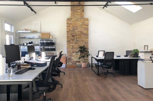 Four desks in a bright, creative warehouse studio in the heart of Queens Park
